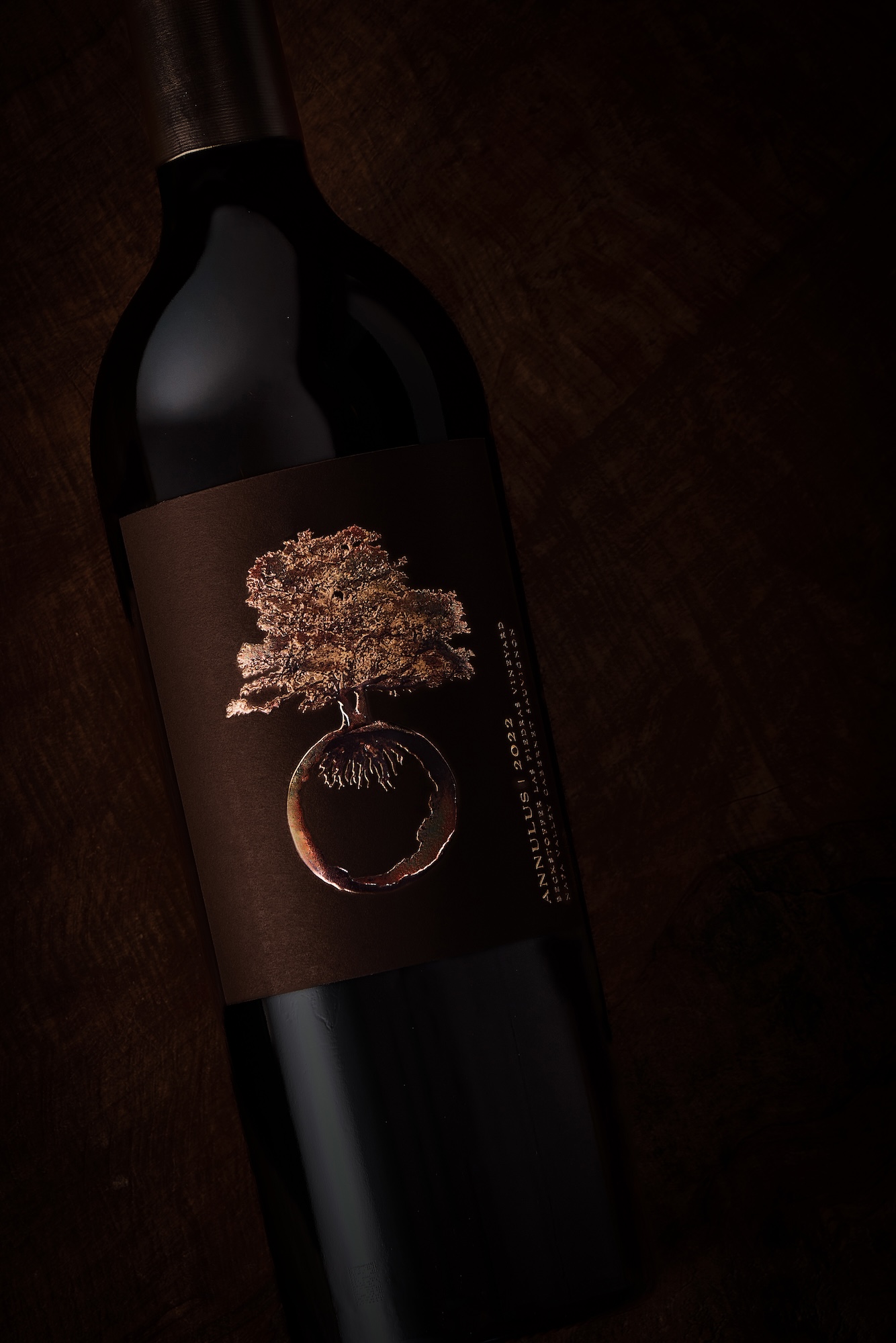 Dark image of bottle with bronze tree logo